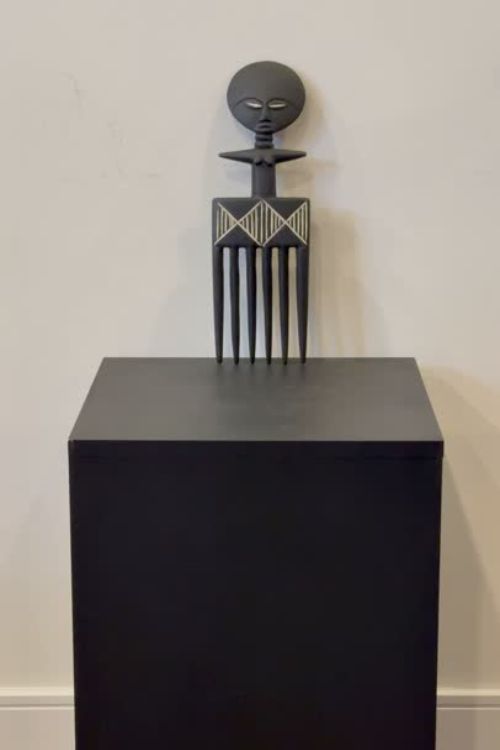 Tekura Akuaba comb wall hanging sculpture with intricate patterns, displayed on a stand, showcasing traditional Ghanaian craftsmanship.