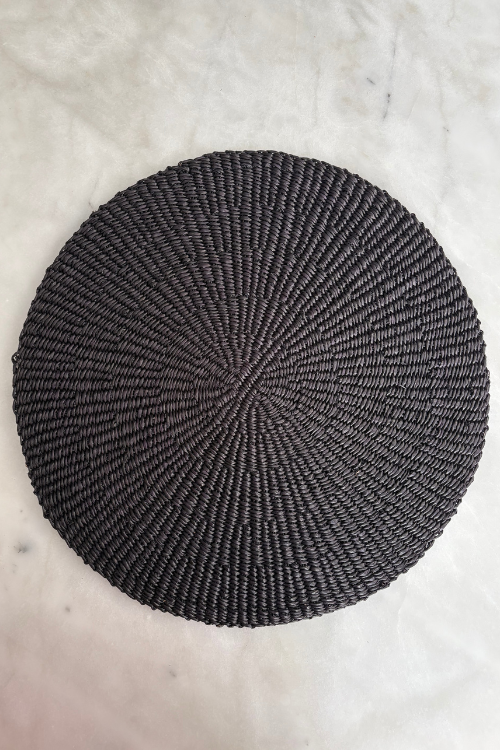 Baba Tree Placemats - Minimalist Noir Round woven black mat on a light gray surface