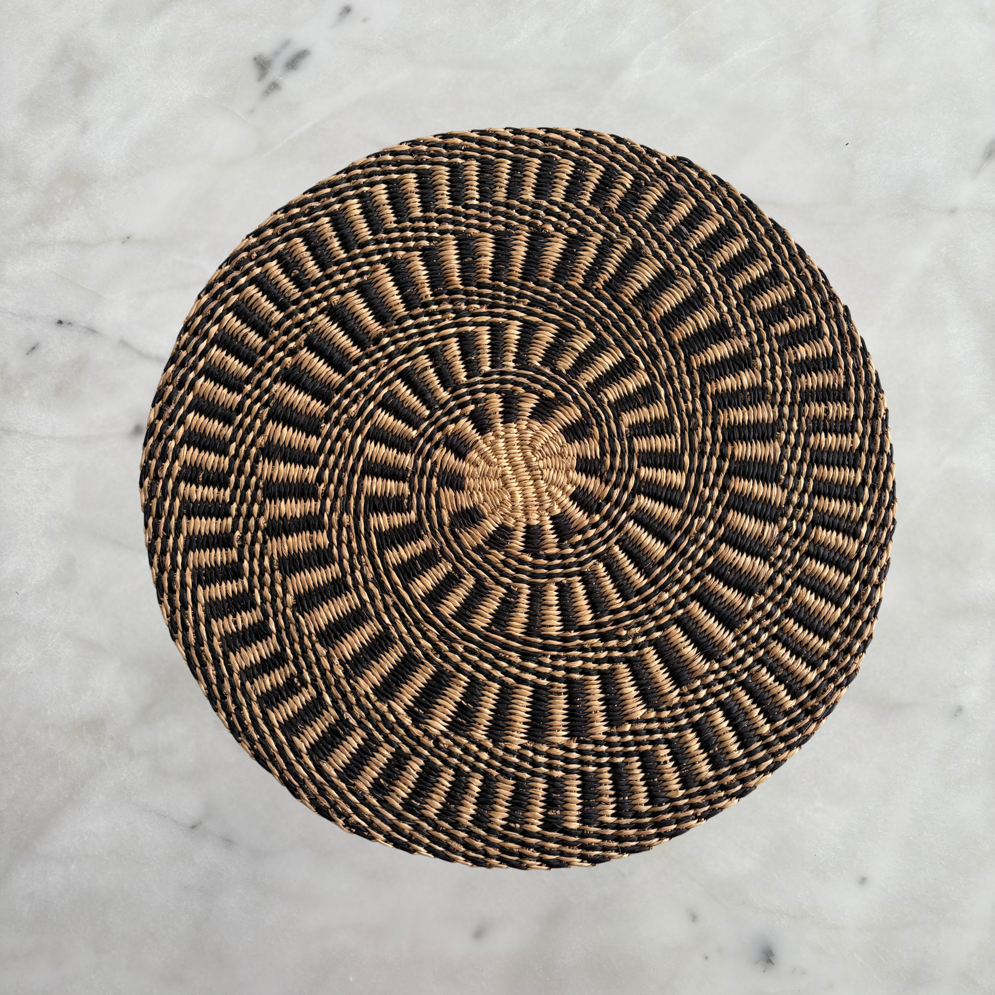 Baba Tree ebony and natural circular placemats set, showcasing woven design in black and beige tones on a dining table.