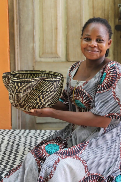 Artisan holding Baba Tree Petite Pakurigo Wave Basket - Black and Natural Essence in black and natural.