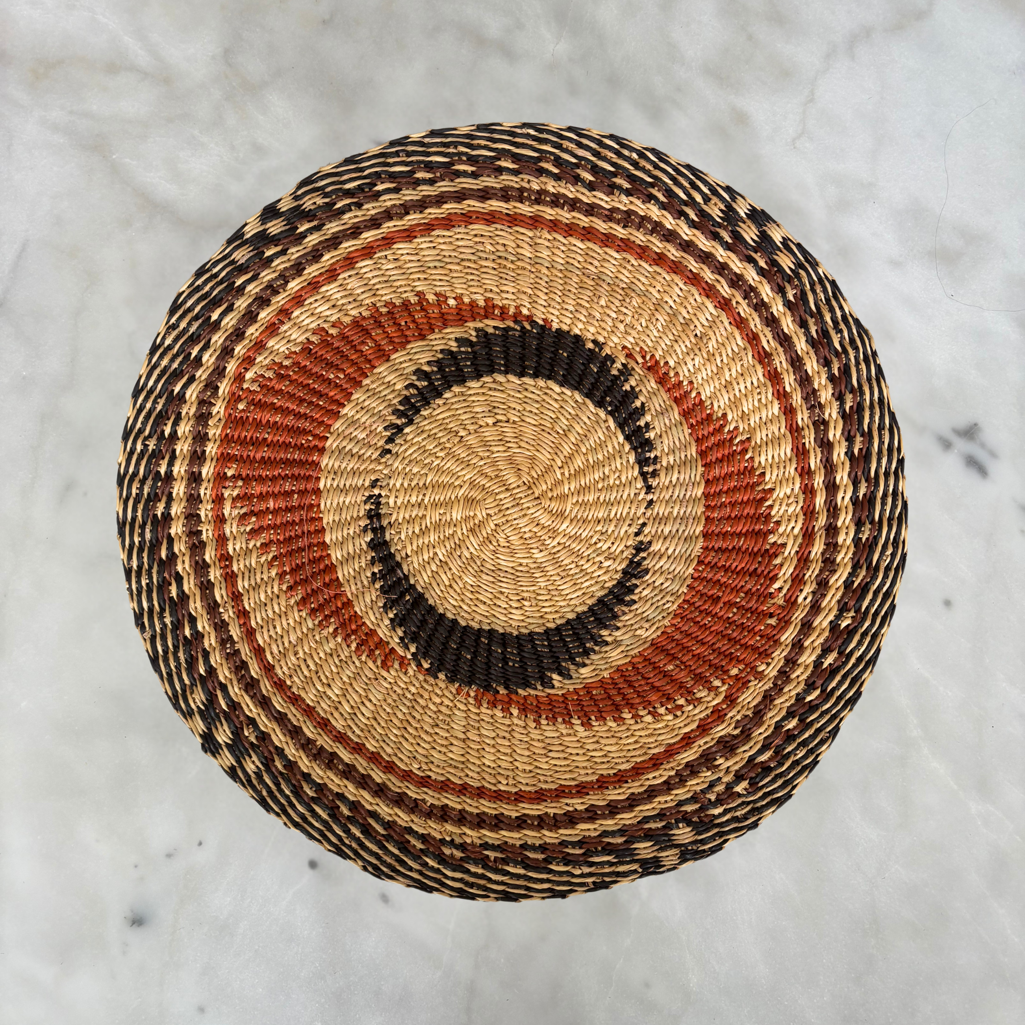 Baba Tree black star swirl woven placemats with natural and orange accents, ideal for dining table decor.