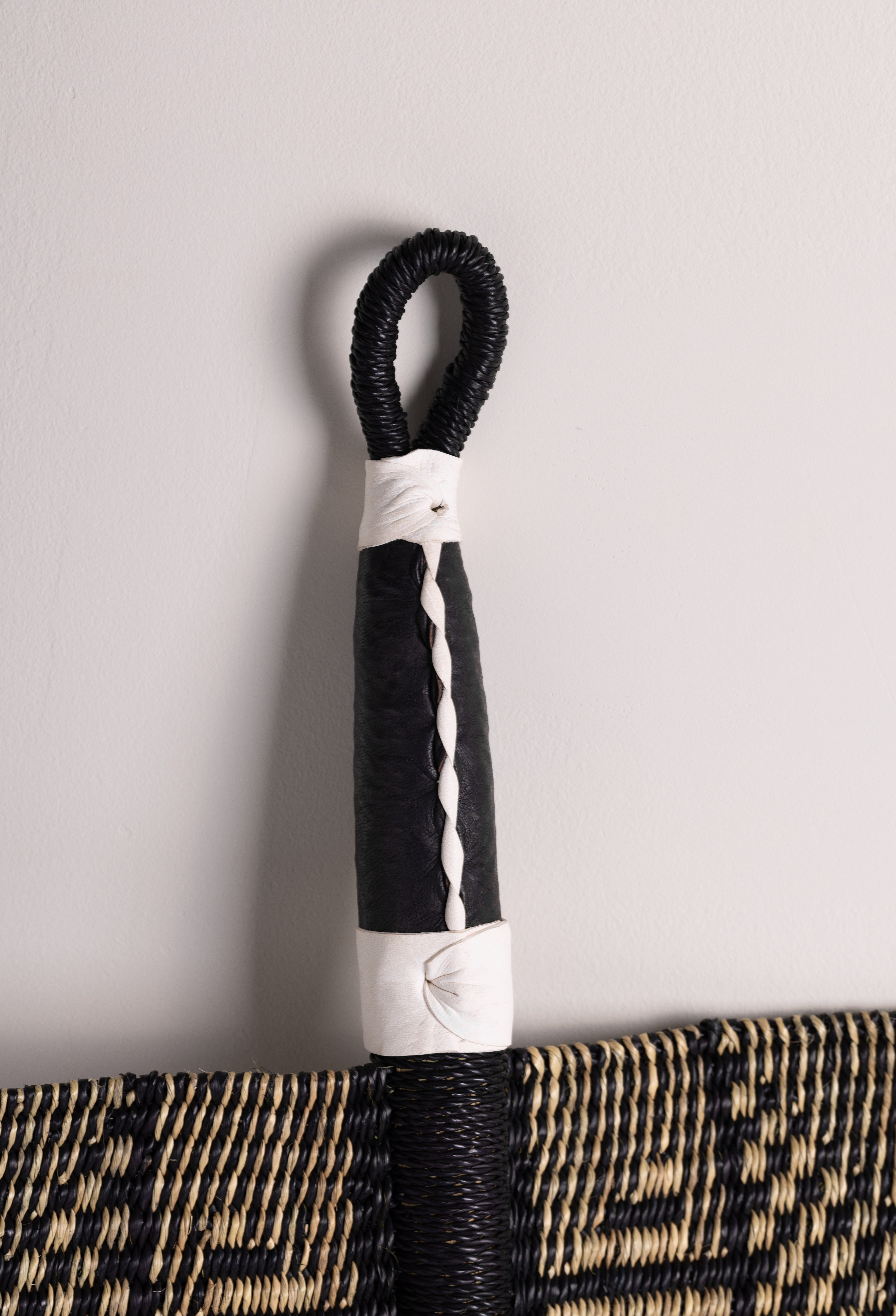 Handcrafted Bolga decorative wall fan with geometric noir design and natural black handle, by Baba Tree.