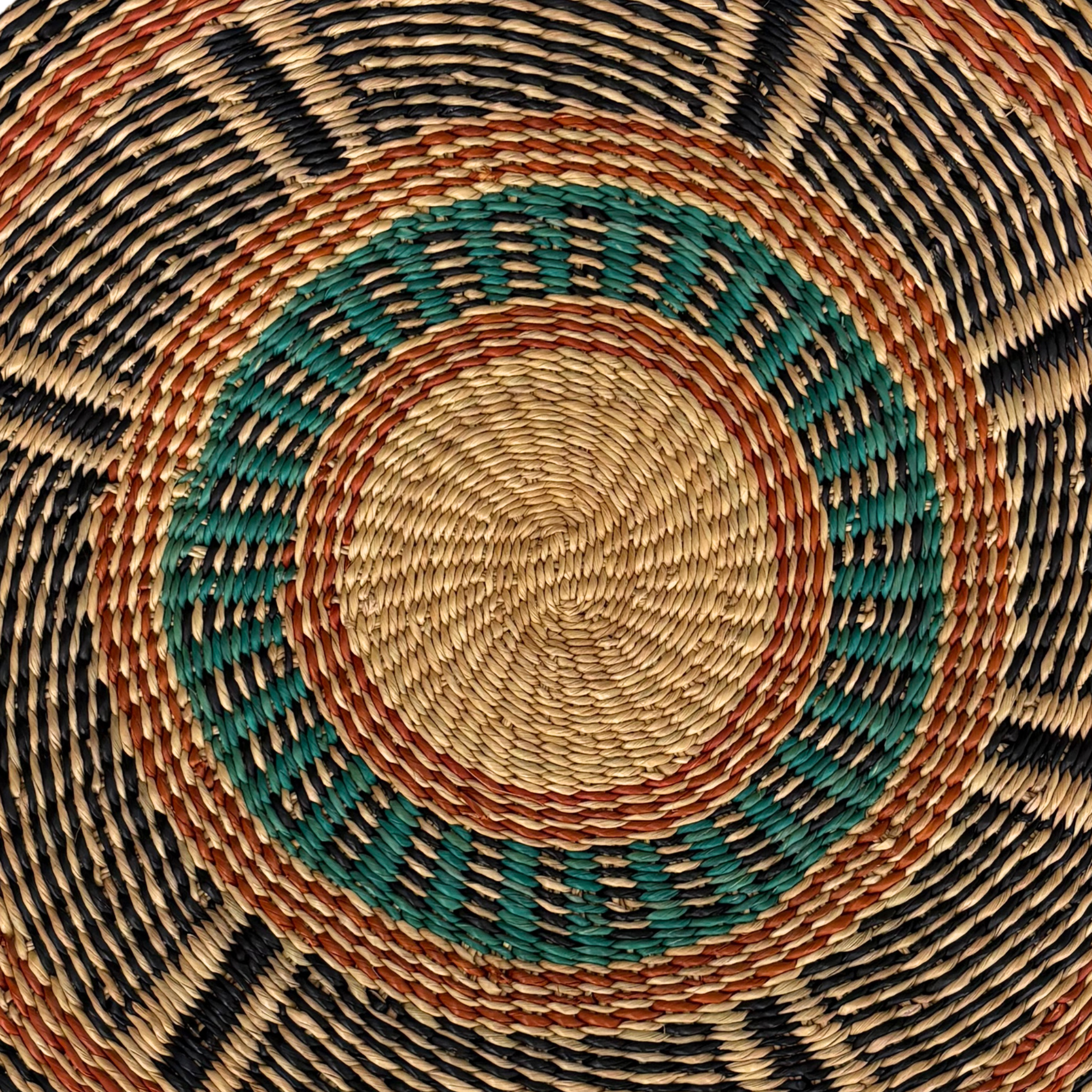 Baba Tree Placemats - Golden Coast. Close-up of a woven basket with concentric circles in brown, green, and black.