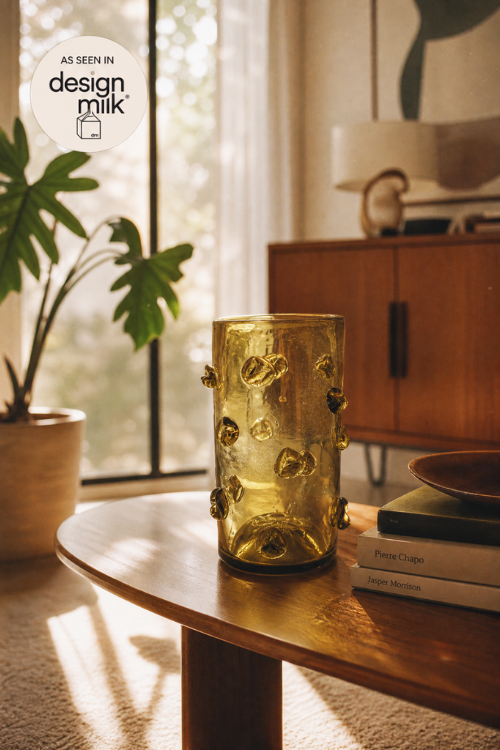 They Nywele citrine moss vase with a bubbly pattern sits on a wooden coffee table in a warm, sunlit living room setting.
