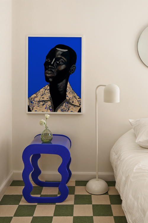 "Remy II" Fine Art Print features a Black man with intense, thoughtful eyes set against a vibrant sapphire Blue background. Remy's deep ebony skin is beautifully accentuated with subtle highlights, creating a sense of depth and dimension. His Blue geometric patterned collared shirt adds a soft contrast to the bold palette, embodying both strength and sensitivity.
