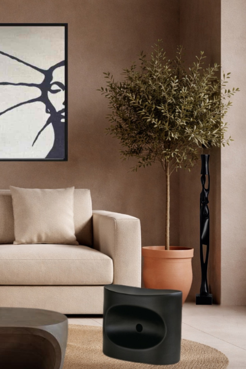 Modern living room with beige sofa, black tekura stool and woman carrying pot sculpture beside a potted plant.