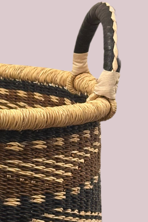 Close up of Woven basket with black and beige handles on a light purple background
