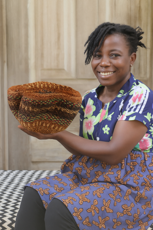 Artisn holding a Petite Pakurigo Wave Basket - Golden Coast in front of a building