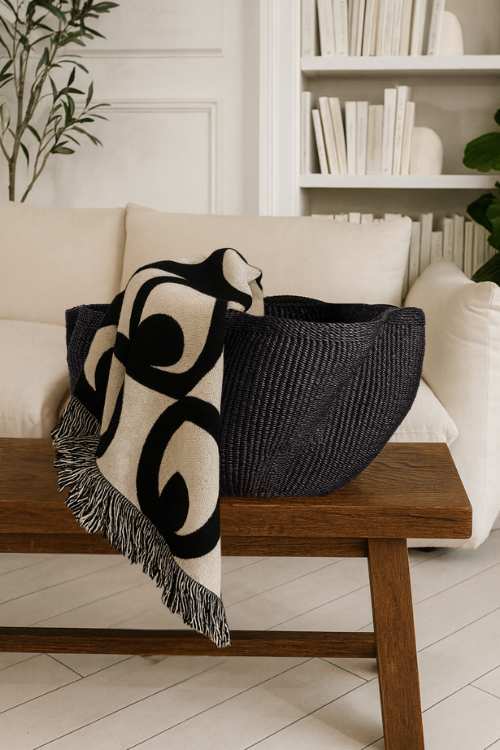 Baba tree black pakurigo wave basket with Decorative throw with black and white mate masie pattern on a beige sofa in a living room setting.
