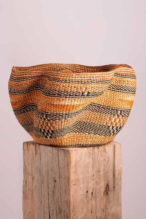 Multi-colored Pakurigo Wave Basket by Baba Tree, a stylish storage basket in orange, brown, and gold tones.