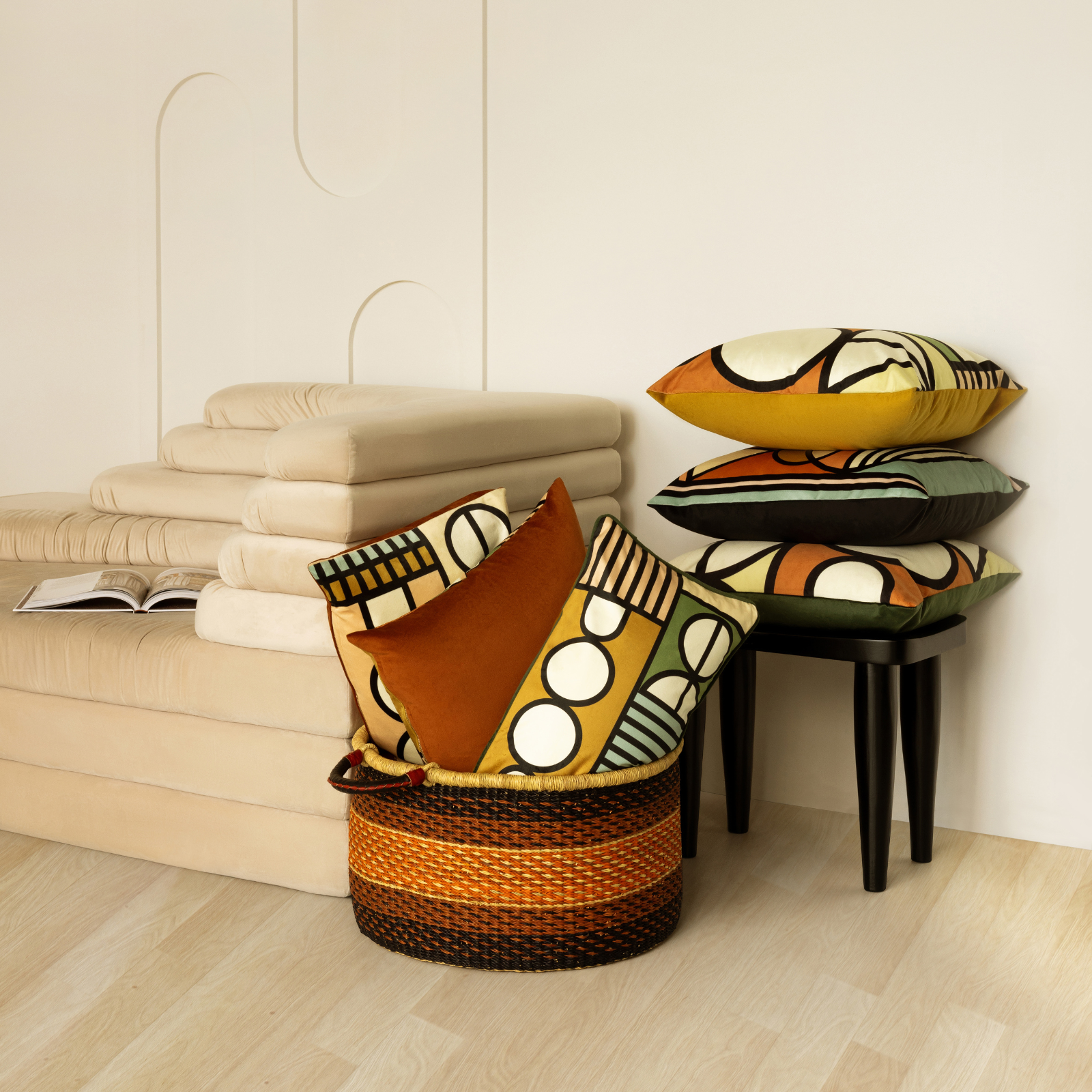 Lulasclan Colorful patterned pillows on a stool and in a basket beside a sofa.