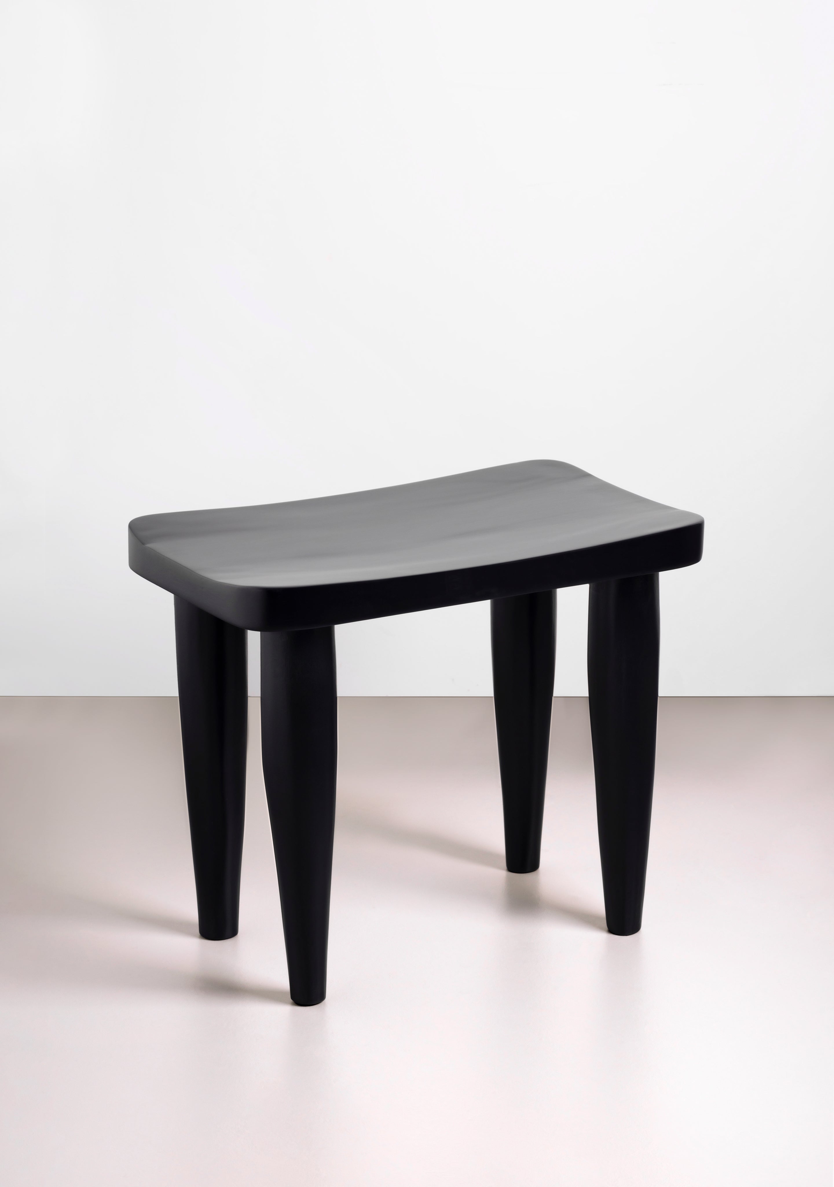 Black Tekura Anantu Bench stool with a sleek, modern design, featuring a sturdy wooden frame and smooth surface.