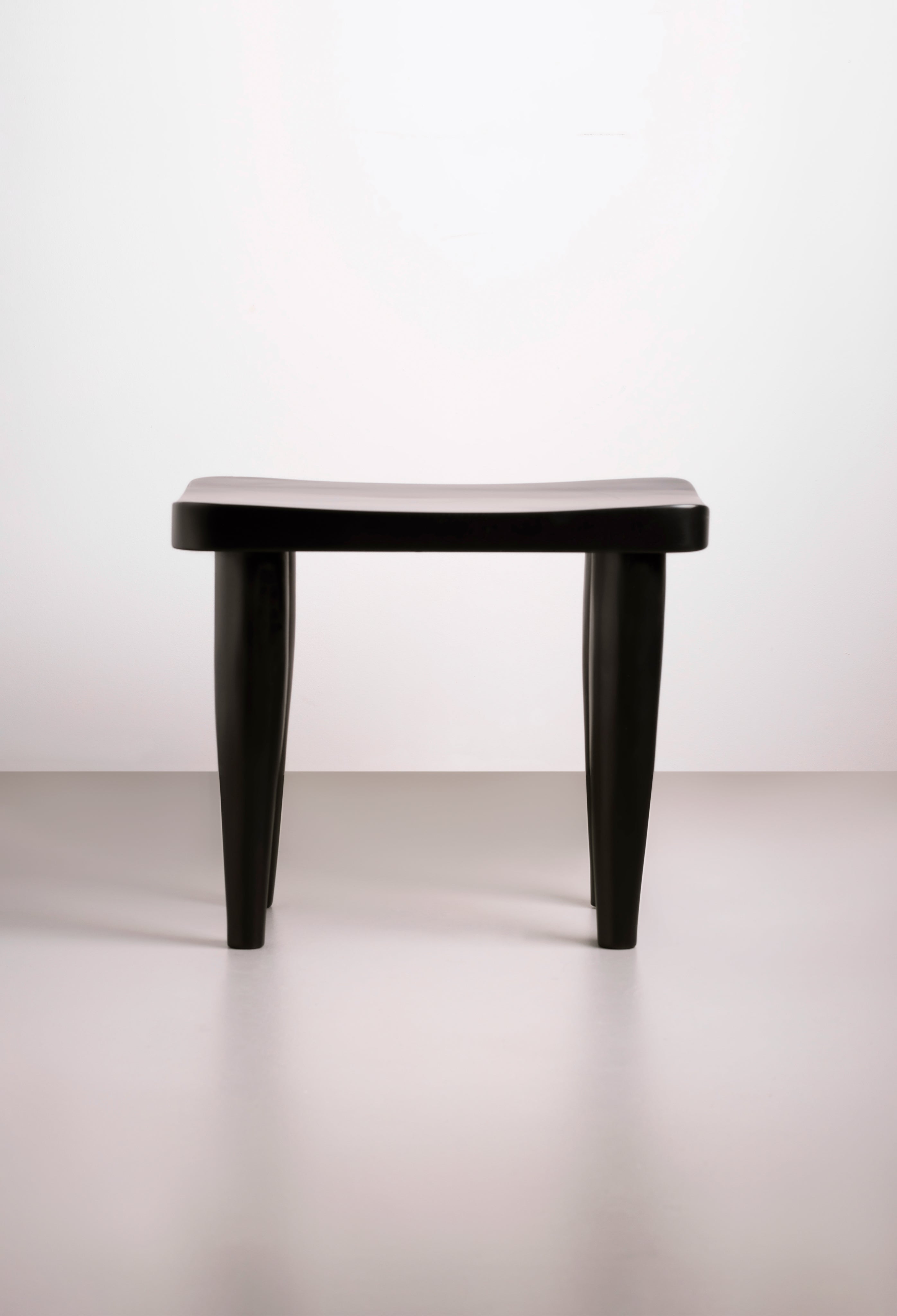 Hand-carved black Tekura Anantu bench stool with intricate design, showcasing craftsmanship and stylish seating.