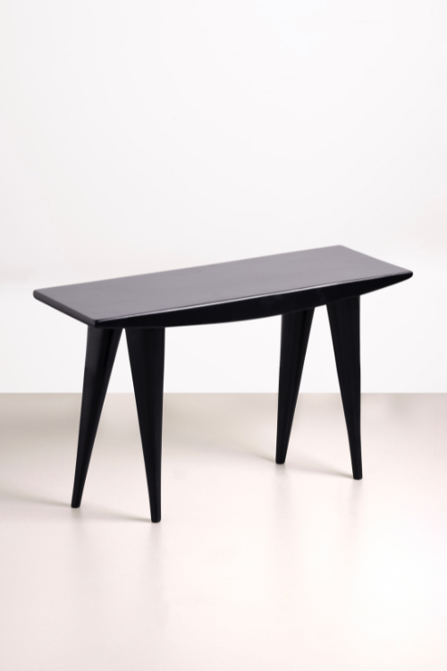 Black Tekura walking bench stool with a handcrafted design, featuring a sturdy wooden frame and a smooth, curved seat.