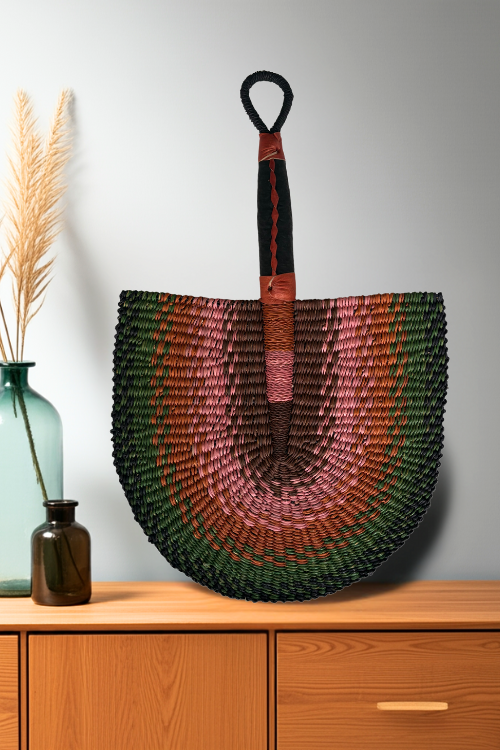 Baba Tree Handcrafted Bolga Decorative Fan – Earthy Blossom in multi-coloured green, pink, brown and orange. Placed on a credenza.
