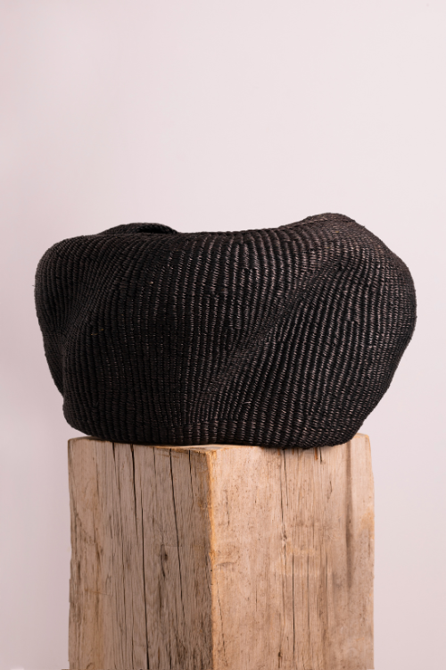 Baba Tree Black pebble basket on a wooden block with a light pink background