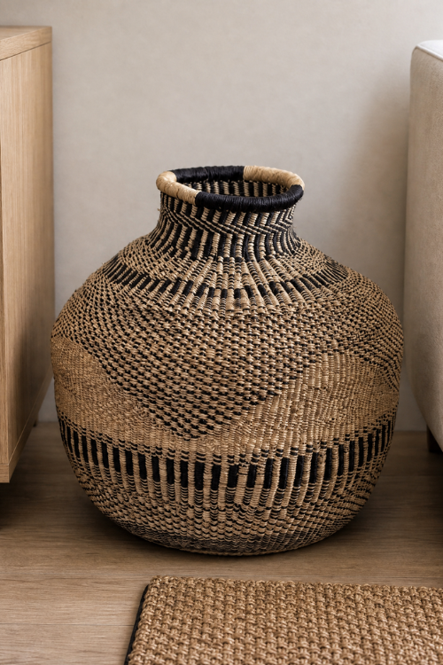 Jemima-10-Cows-Basket-Ebony-Triangle with a narrow black and beige rim, displayed on a wooden floor against a neutral beige wall.