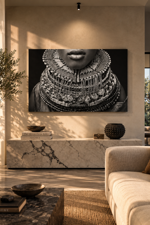 A large black and white wall art print depicting a close-up of a person wearing elaborate layered necklaces, displayed in a modern, warm-toned living room above a marble console table.