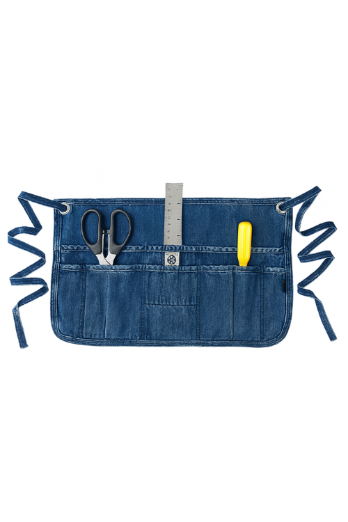 Mi Cocina Denim waist apron with pockets holding scissors, a ruler, and a yellow marker on a white background
