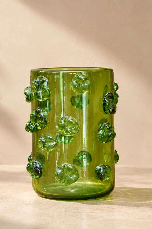 The nywele vase moss in olive green glass cup decorated with raised, bubble-like green glass accents, set against a warm beige background with soft shadows.