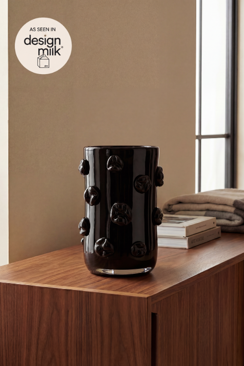 Nywele vase onyx with a glossy finish and raised organic bulb details, displayed on a wooden cabinet in a styled interior setting next to a window.