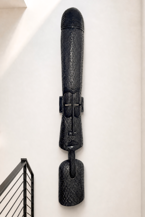 Black textured African wall-mounted sculpture on a white wall