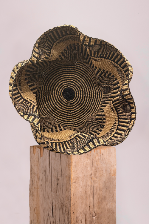 Pakurigo-Wave-Basket-Black-and-Natural-Essence on a wooden stand against a light background