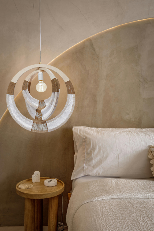 South African woven pendant necklace light by Modern Gesture, hanging in a bedroom, featuring intricate woven design and warm lighting.