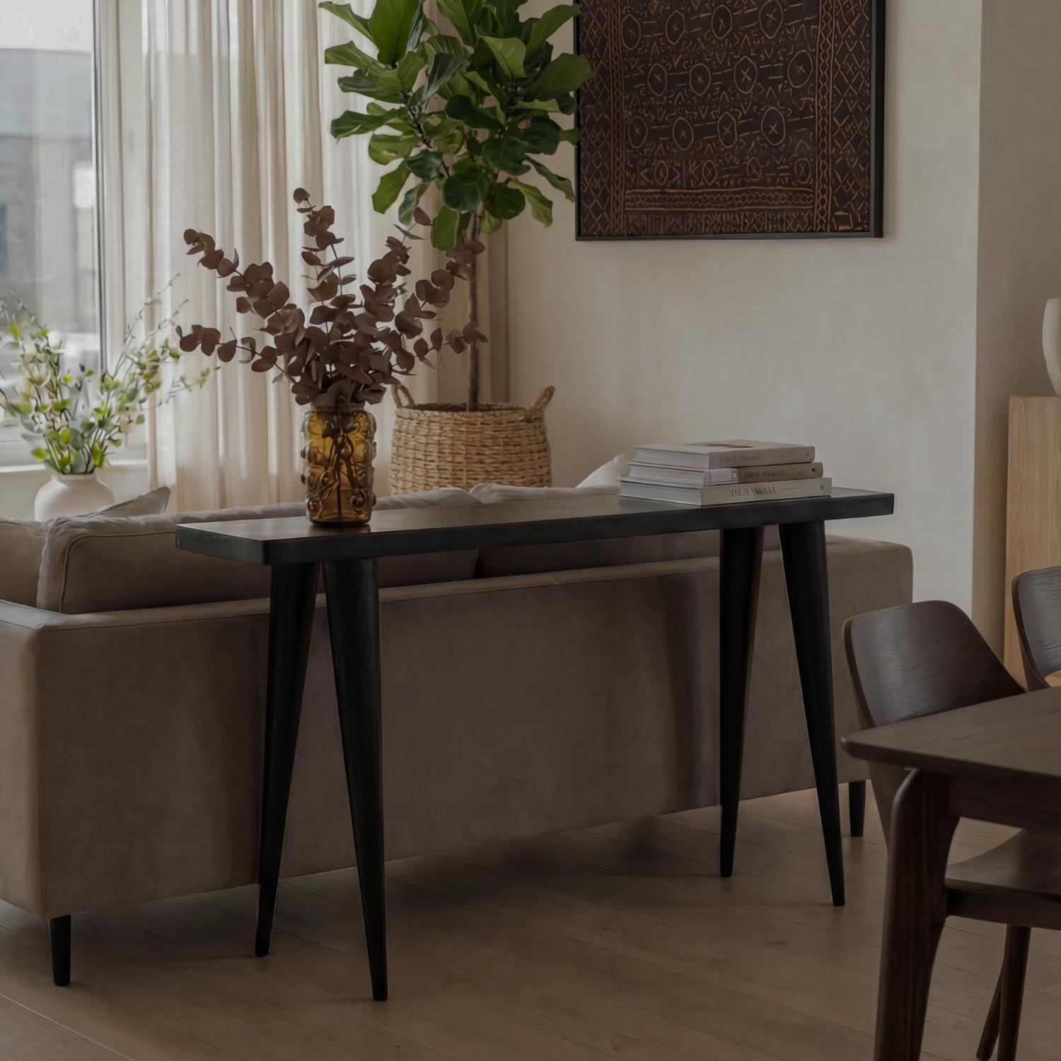 Modern living room with a dark wood walking console table from Tekur, sofa, and chairs at September Collective