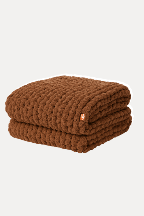 Folded brown blanket with a small orange tag on a white background