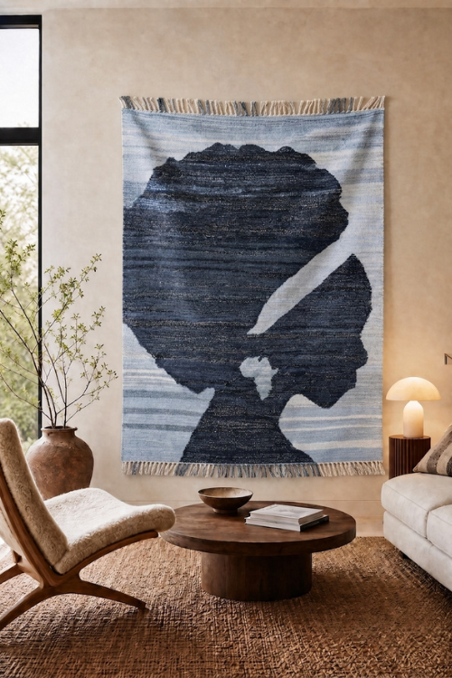A large woven wall tapestry featuring a stylized dark blue silhouette of a woman's profile on a light blue and white striped background, hanging in a modern living room setting.