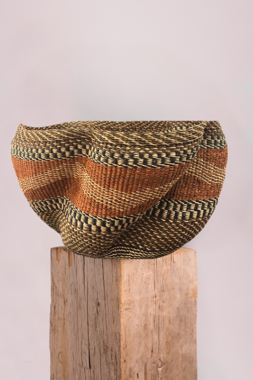 Baba Tree Pakurigo Wave Basket - Gurunsi with a striped pattern on a wooden block against a light background