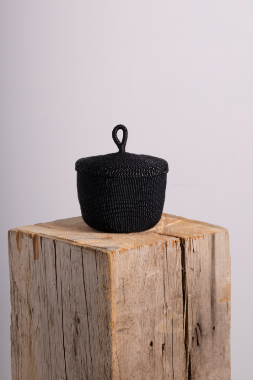 Baba Tree black banasco basket with a handle on a wooden block against a light background