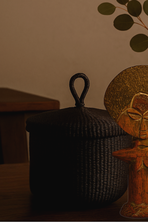 Baba Tree Black banasco basket on a surface next to a decorative african statue.