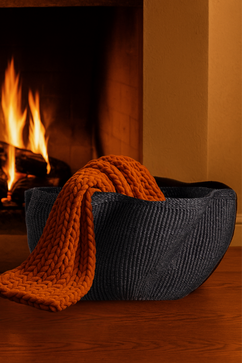 Baba Tree black pakurigo wave basket with an orange knitted blanket in front of a fireplace at september collective