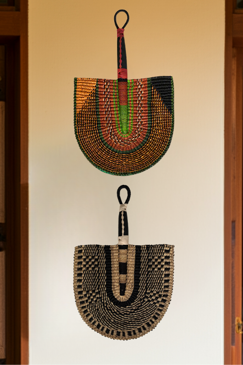 2 Handcrafted Bolga Decorative Fan – Black & Natural Essence - styled on a wall. Handwoven Elegance from Ghana is a cost-conscious way to bring authentic African craftsmanship into your home.