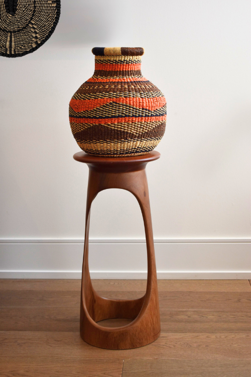 Woven Baba Tree basket on a wooden stand against a white wall