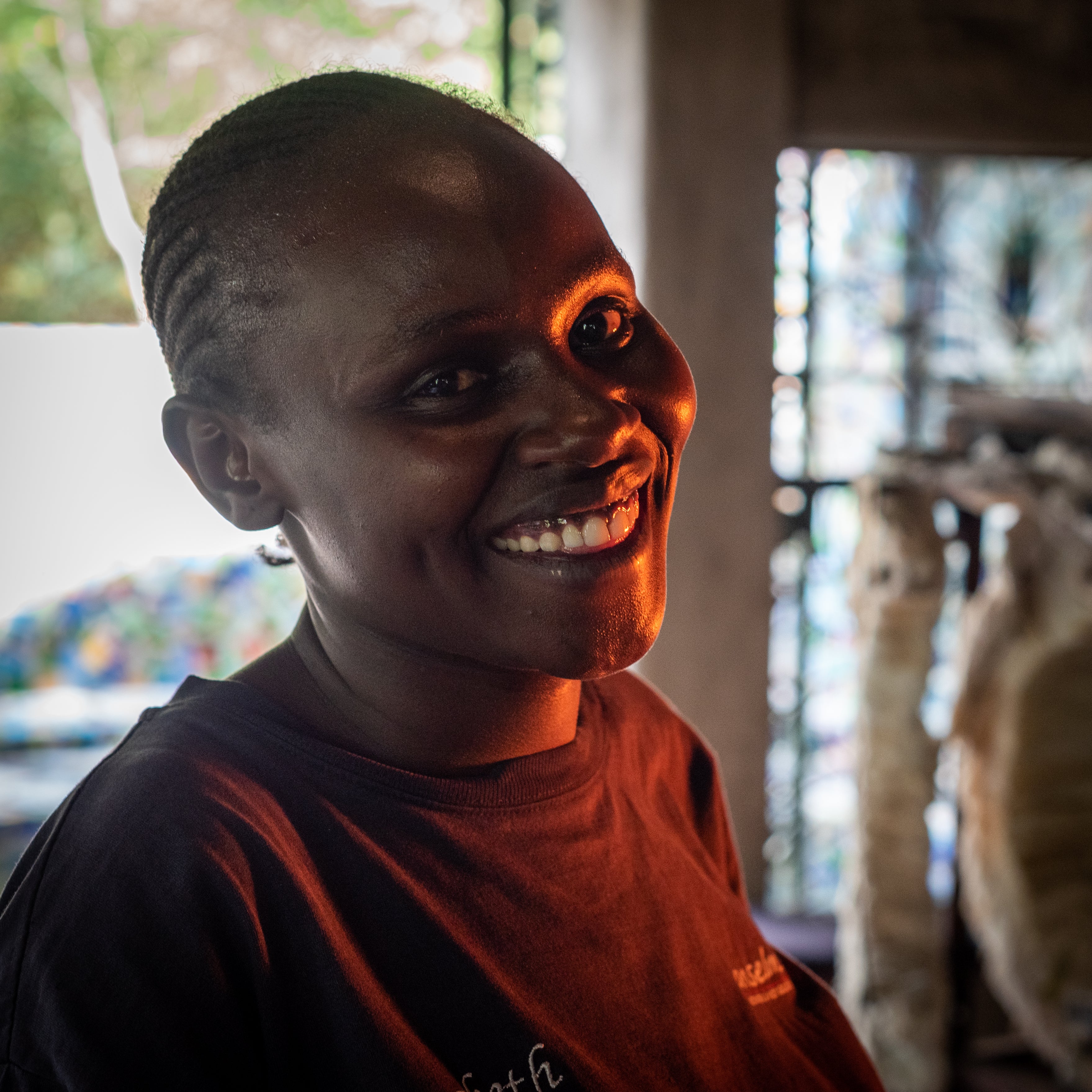 Kitengela glass artisan wearing a red shirt with a blurred background