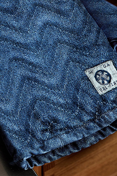 Close-up of Mi cocina Denim Herringbone Quilted Oven Mittt with a brand label on a wooden surface