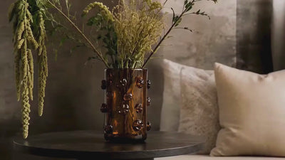 Video showing Nywele vase on table, a black woman, a door opening an the Obaa wall totem shown and a black and white art piece of an african woman in traditional wear.