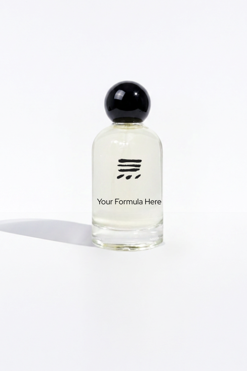 A clear glass perfume bottle with a black spherical cap, containing a pale yellow liquid. The bottle features a minimalist black logo and the text 'Your Formula Here' printed on the front, set against a clean white background with a soft shadow to the left.